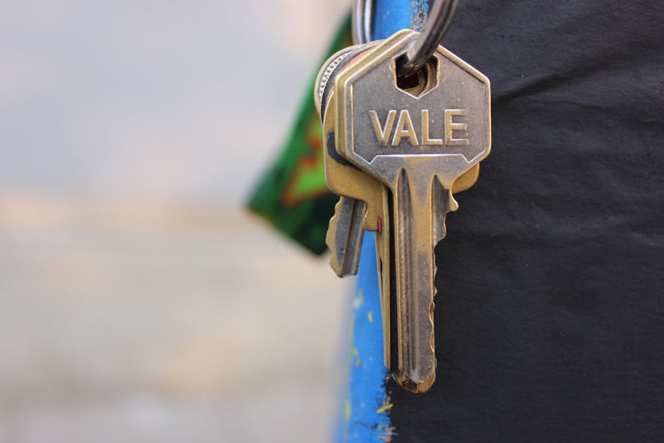 A detailed view of a metallic key with 'Vale' engraved on it, hanging against a blurred background.